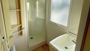 Une petite salle de bain avec une douche, une fenêtre et un lavabo intégré.