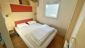 Une chambre d’hôtel comprenant un lit, une table de chevet, une commode, une fenêtre et une étagère intégrée remplie de livres.