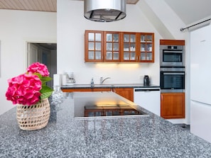 A modern kitchen with granite countertops, wooden cabinets, and stainless steel appliances. - 4 Star Holiday Home in Ulfborg (Ulfborg)