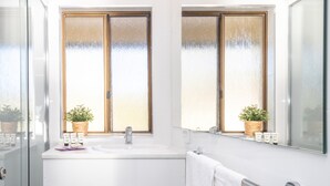 A bathroom with a white sink, two potted plants, a mirror, and a towel rack. - Batemans Bay Studio Escape With Lush Vista (Batehaven)
