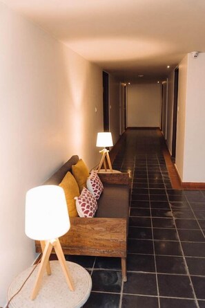 A hallway with a sofa and two lamps, leading to a dark tiled floor. - Hotel Roadhouse (Kathmandu)