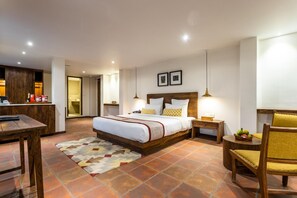 Habitació d'hotel amb llit, taules de nit, escriptori, cadira i taula de menjador.