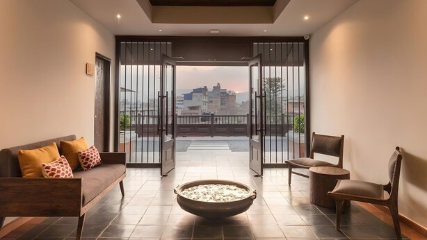 A modern living room with a sofa, chairs, a large bowl, and a view through open doors to the outside. - Hotel Roadhouse (Kathmandu)