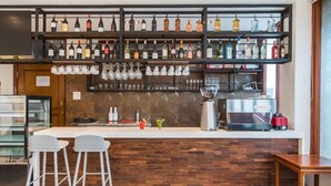 A bar area with shelves of liquor bottles, a coffee machine, and bar stools. - Timber House (Kathmandu)