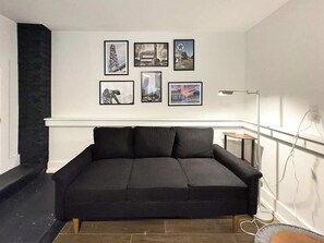 A modern living room with a black sectional sofa, a fireplace, and a collection of framed pictures on the wall. - Newly Furnished 1-BR/1-BA in Atlanta's Virginia Highland Neighborhood (Atlanta)