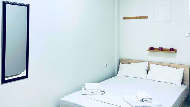 Ein schlicht eingerichtetes Schlafzimmer mit einem Bett, einem Spiegel und einer Deckenleuchte.