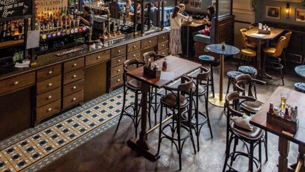 Eine Bar mit klassischem Design, ausgestattet mit einem Chandelier, Barhocker und einer Auswahl an Flaschen.
