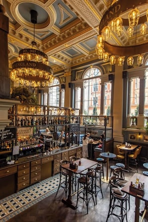 A bar with a classic design, featuring a chandelier, bar stools, and a variety of bottles. - A Stay in the City? This Penthouse is a Statement! (London)