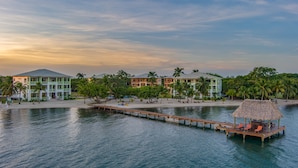 A resort with multiple buildings, a dock, and a beach area with palm trees.
