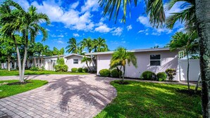 A residential area with multiple single-story houses, paved driveways, and well-maintained lawns. - Stylish 4BR Oasis | Heated Pool, Spa & Fire Pit (Pompano Beach)