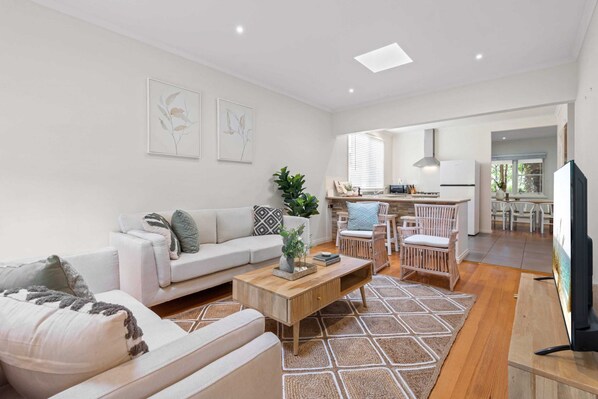 A modern living room with a sofa, coffee table, and a dining area with chairs.