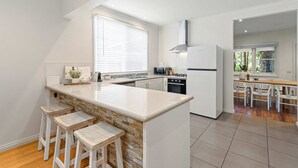 Une cuisine moderne dotée d’un îlot central, de meubles blancs et d’un coin repas avec des chaises en bois.