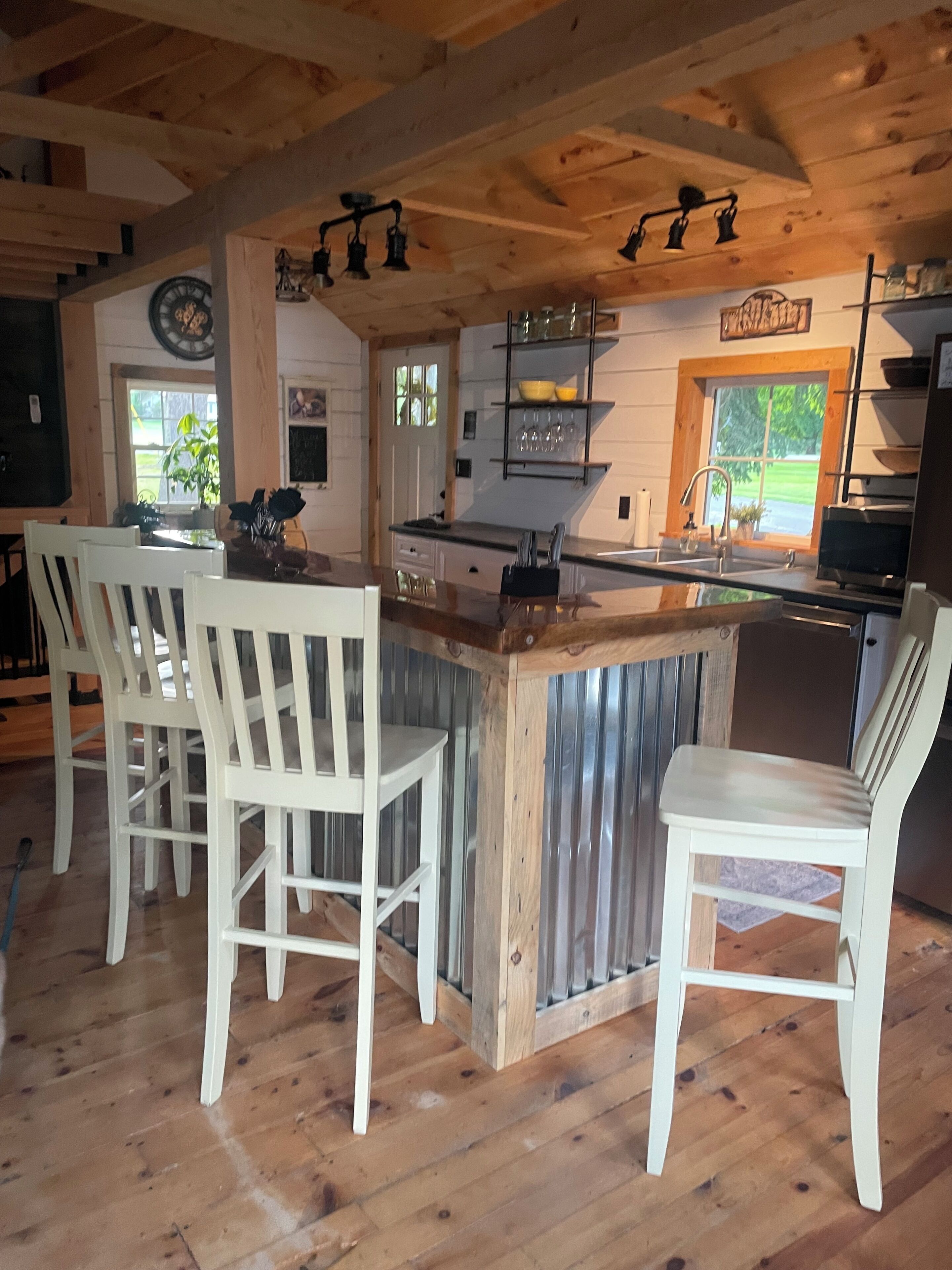A kitchen with a wooden island, bar stools, and a view of the outdoors.