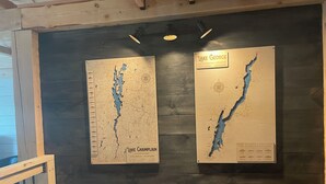 Twee kaarten van het Champlainmeer en het Georgemeer bevestigd aan een houten wand.