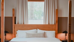 Un dormitorio con una cama grande, dos sillas, una mesita y una ventana con cortinas.