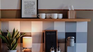Una encimera de cocina con cafetera, un letrero que dice "Welcome" y un refrigerador pequeño de la marca Frigidaire.