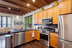 A modern kitchen with wooden cabinets, stainless steel appliances, and a large window with blinds. - Green Lake Modern K/Q  + Parking | Stadium Access (Seattle)