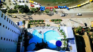 Vista aérea de um hotel com piscina, guarda-sóis e área de praia.