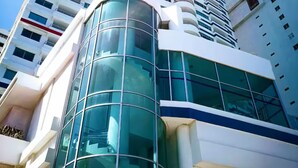 Um edifício alto com fachada de vidro moderna e estrutura curva na base.