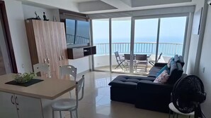 Uma sala de estar moderna com cozinha, espaço para refeições e uma varanda com vista.