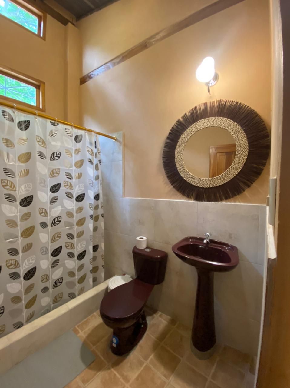Un baño con cortina de ducha, inodoro, lavabo y espejo montado en la pared.
