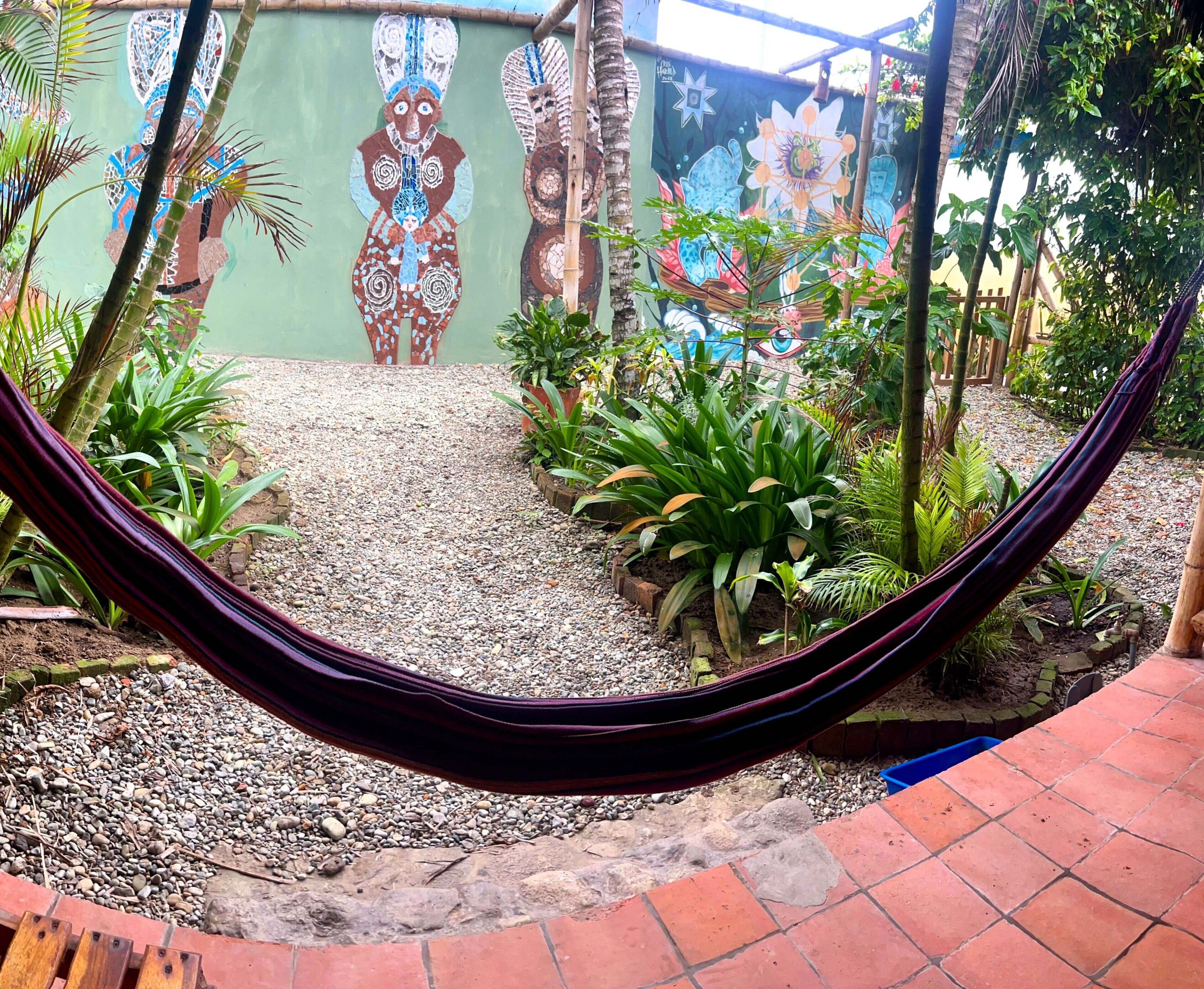 Un hamac dans un jardin, avec un mur décoratif en arrière-plan.