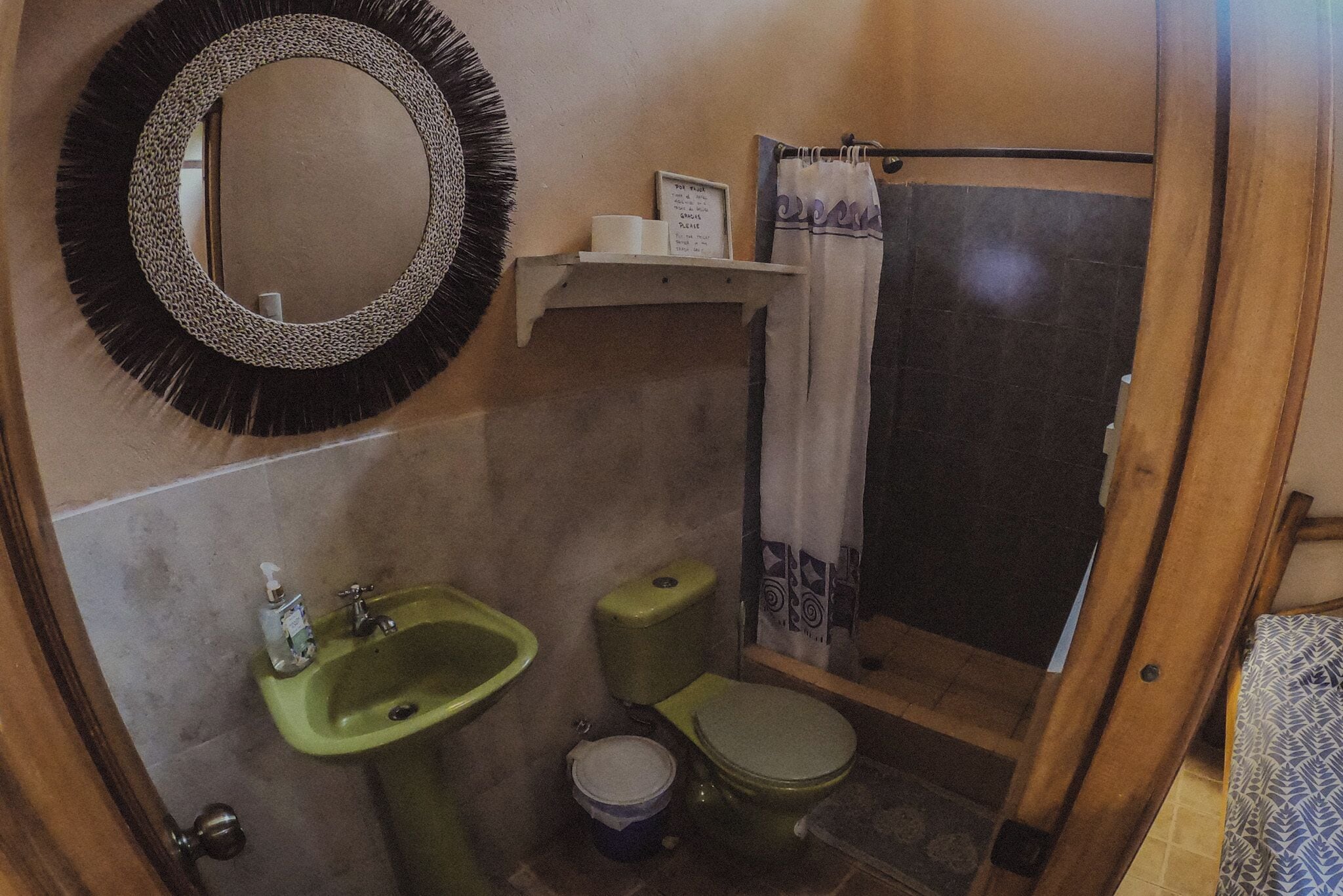 Ein Badezimmer mit Waschbecken, Toilette und Duschvorhang, alles in Grün.