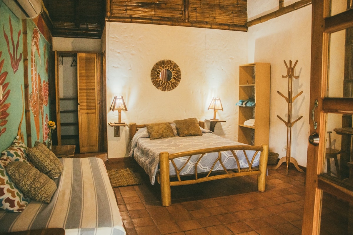 Un dormitorio acogedor con una cama de madera, dos lámparas de noche, un adorno de sol en la pared y un perchero de madera.