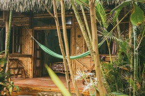 A wooden structure with a thatched roof, surrounded by tropical plants and a hammock. - HOSTAL ROSA MISTICA  (Montañita)