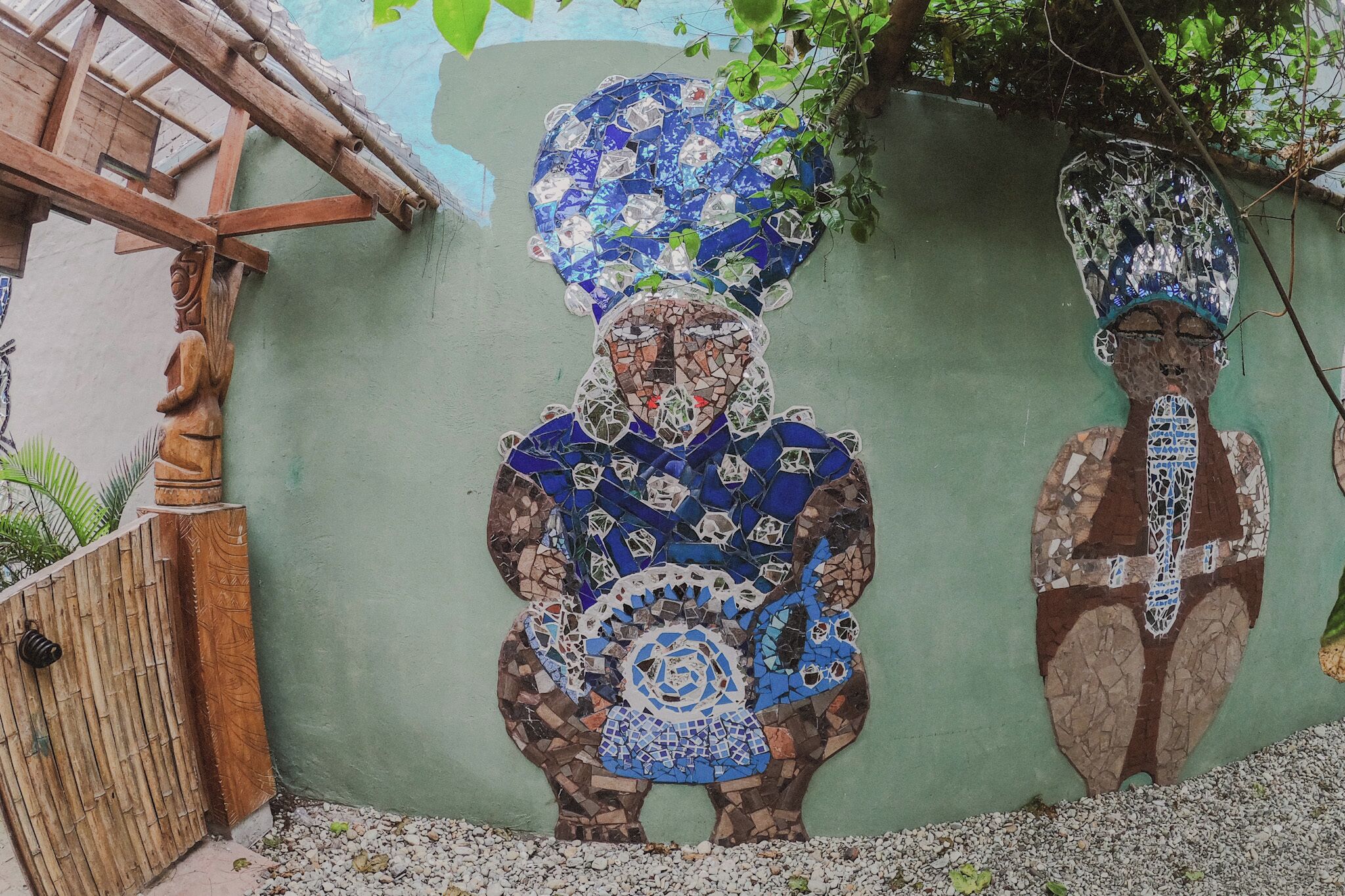 A mosaic mural of a figure with a large headdress on a wall.