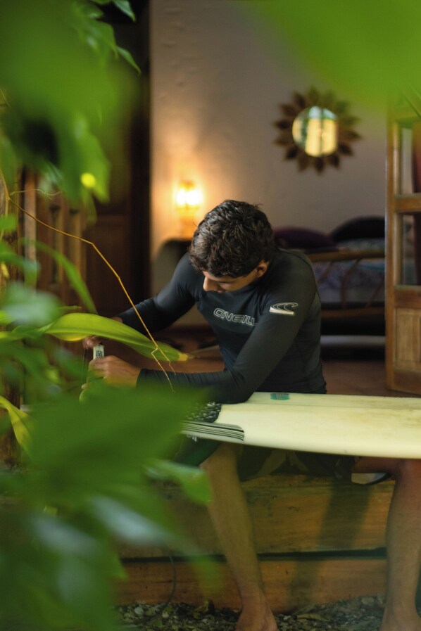 A person sitting at a table with a surfboard, surrounded by indoor plants.