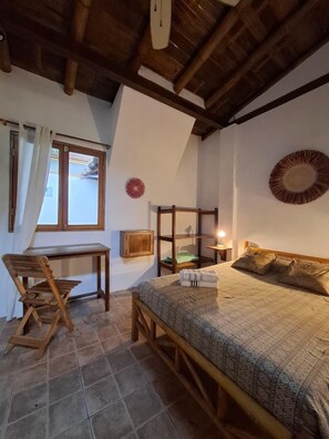 A cozy room with a bed, a wooden desk, a chair, and a window with curtains.