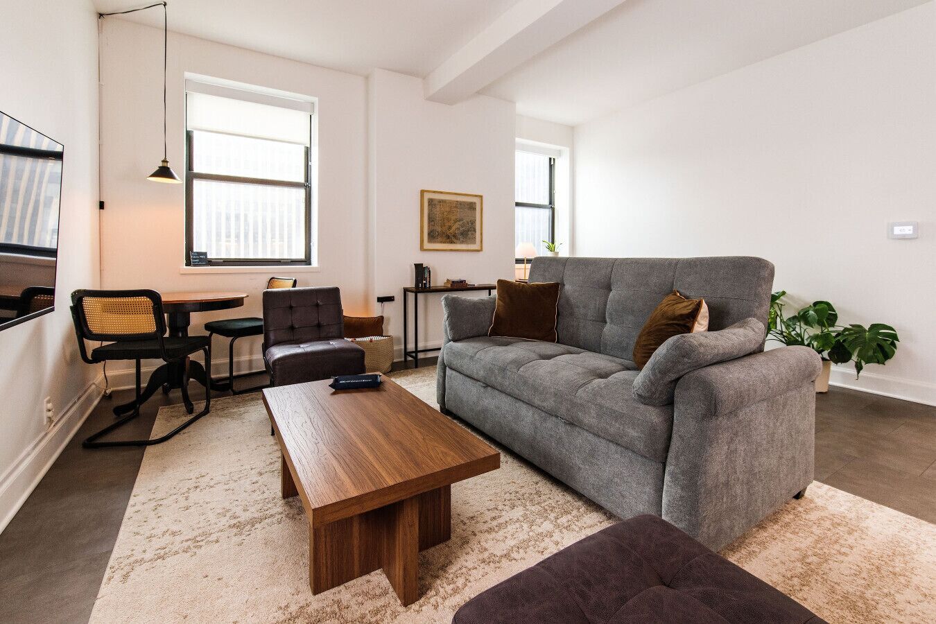 Een moderne woonkamer met een grijze bank, een houten salontafel en een zwarte stoel.