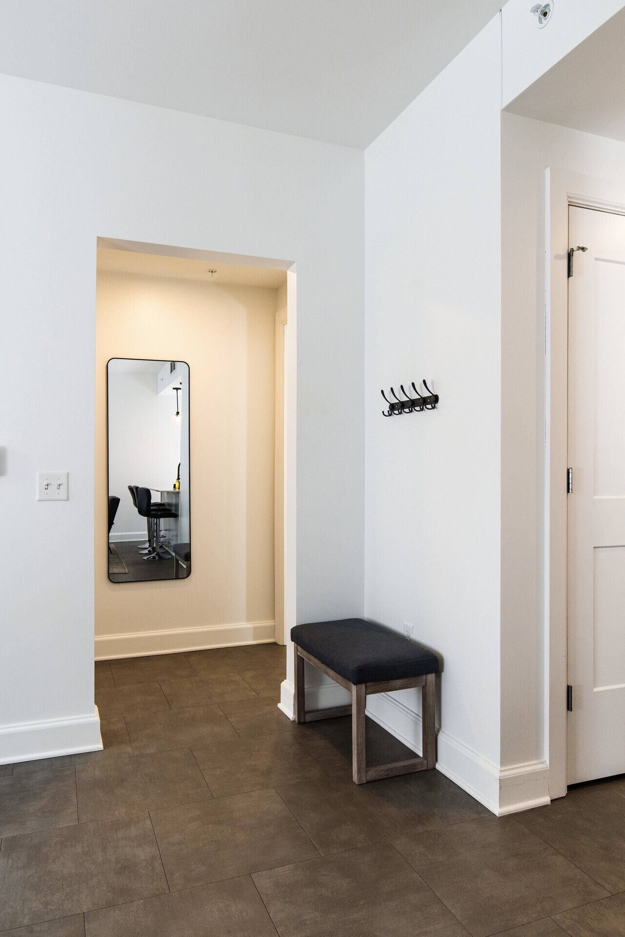A hallway with a bench, a mirror, and a coat rack.