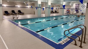 Ein Hallenbad mit mehreren Bahnen, Liegestühlen und einem Rettungsschwimmerstuhl.
