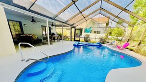 Una piscina interior con techo de vidrio, rodeada de sillones de descanso y una zona de terraza.