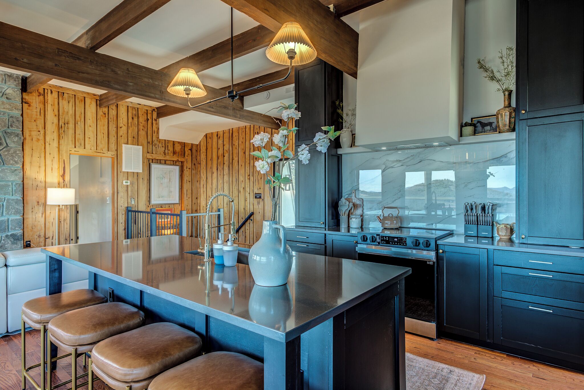 Une cuisine moderne avec des éléments en bois, un îlot central, des tabourets de bar et des appareils électroménagers intégrés.
