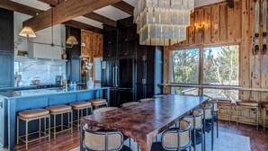 Una cocina moderna con una isla grande, taburetes de bar y una mesa de comedor de madera.