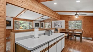 L’intérieur d’une cabane en bois comprend un coin cuisine, une table à manger et des chaises.
