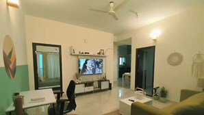 Un salon moderne comprenant un téléviseur à écran plat, un canapé, une table basse et un bureau avec une chaise.