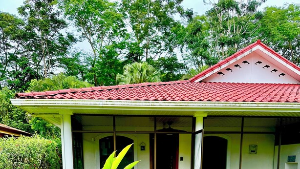 A house with a red tiled roof, a covered porch, and a brick pathway leading to the entrance. - Riverside oasis with private pool and backyard.  Walking distance to the beach. (Paquera)