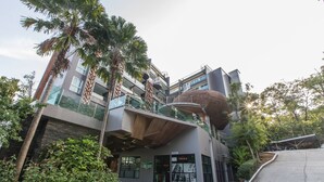 A modern building with a unique architectural design, featuring a curved structure and multiple balconies. - Emerald 412a - Studio With Balcony and Shared Pool (Patong)