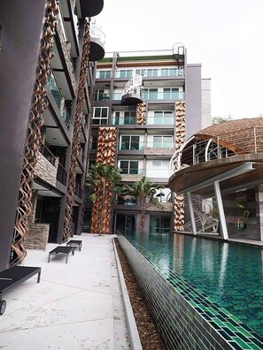 Ein modernes Gebäude mit Pool, das sich durch ein einzigartiges architektonisches Design mit geschwungenen Balkonen und einem zentralen Atrium auszeichnet.