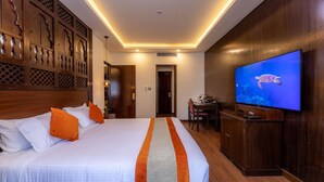 Een hotelkamer met een groot bed, een televisie aan de muur en een houten hoofdeinde.