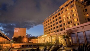 A multi-story hotel with a pool area, outdoor seating, and a well-lit entrance. - The Everest Hotel (Kathmandu)