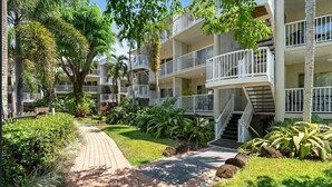 A multi-story hotel with balconies, a central walkway, and lush greenery. - Coconut Vibes- Overlooking Resort Pool Ocean Glimpses, Holloways Beach - Cairns (Holloways Beach)