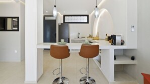 Uma cozinha moderna com dois bancos de bar, uma ilha integrada e iluminação pendente.