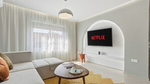 Uma sala de estar moderna com um sofá, uma mesa de centro e uma televisão de tela plana presa à parede.