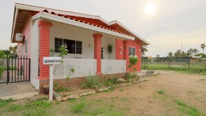 A house with a porch, a sign reading "GASPARITO 115," and a fenced yard with plants. - LIMITED OFFER FOR FIRST GUESTS - ENJOY MY HOME AT A GREAT RATE! (Noord,)