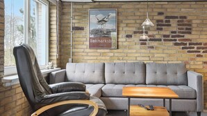 Ein modernes Wohnzimmer mit Ledersessel, grauem Sofa und einem kleinen Holztisch.